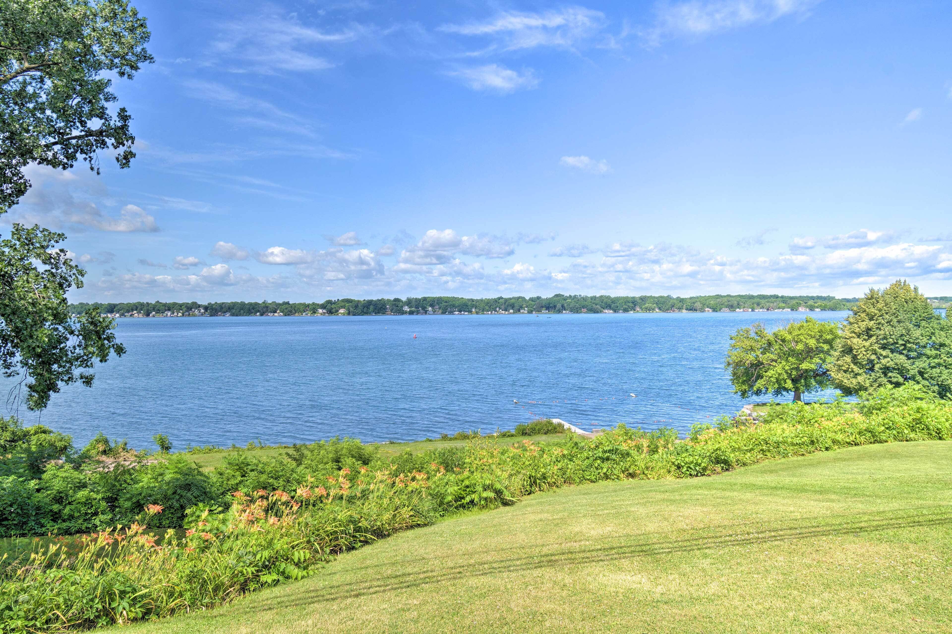 A view of a lake with a grassy area in the foreground and trees on the left.
