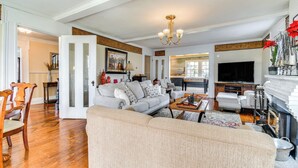 A spacious living room with a fireplace, a television, and a dining area with wooden chairs and a table.