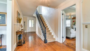A spacious hallway with a wooden floor leading to a curved staircase with beige carpeted steps and black balusters.