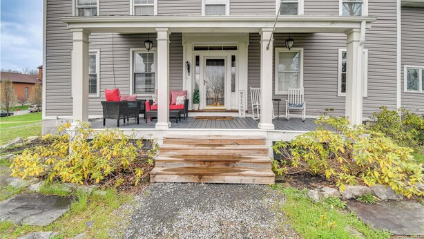 A two-story house with a porch, wooden steps, and a welcome sign.