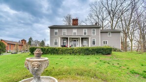 A large two-story house with a front porch, a stone fountain, and a well-maintained lawn.
