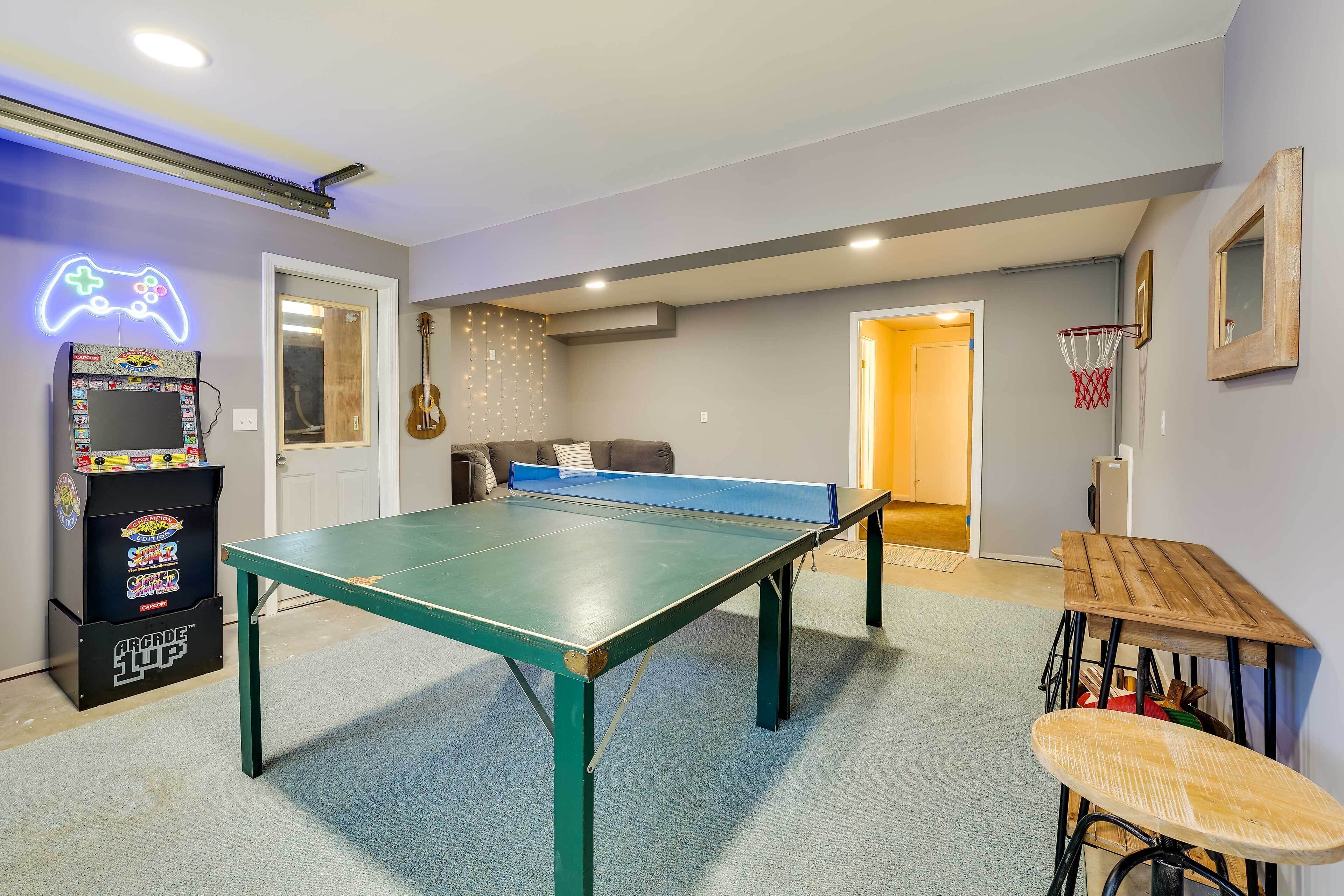 Et rum med pingpongbord, et neonskilte med en spillekonsol, en guitar og en basketballkurv.