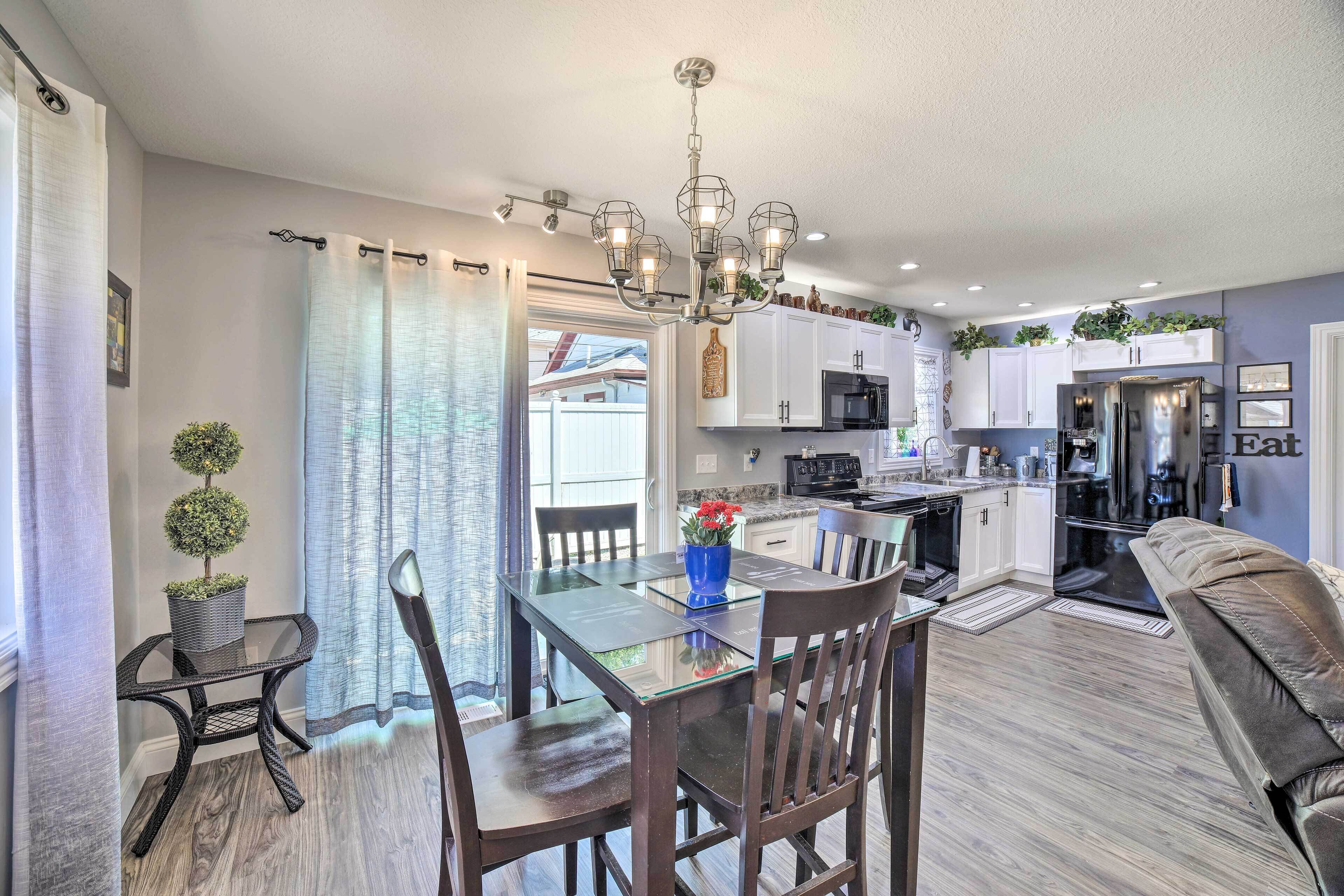 A modern kitchen with white cabinets, a stainless steel refrigerator, and a dining area with a glass table and chairs.
