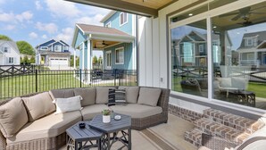 A covered patio area with a wicker sofa, a small table, and a brick fireplace.