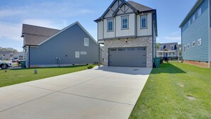 A residential area with houses featuring stone and wood exteriors, a driveway, and a well-maintained lawn.