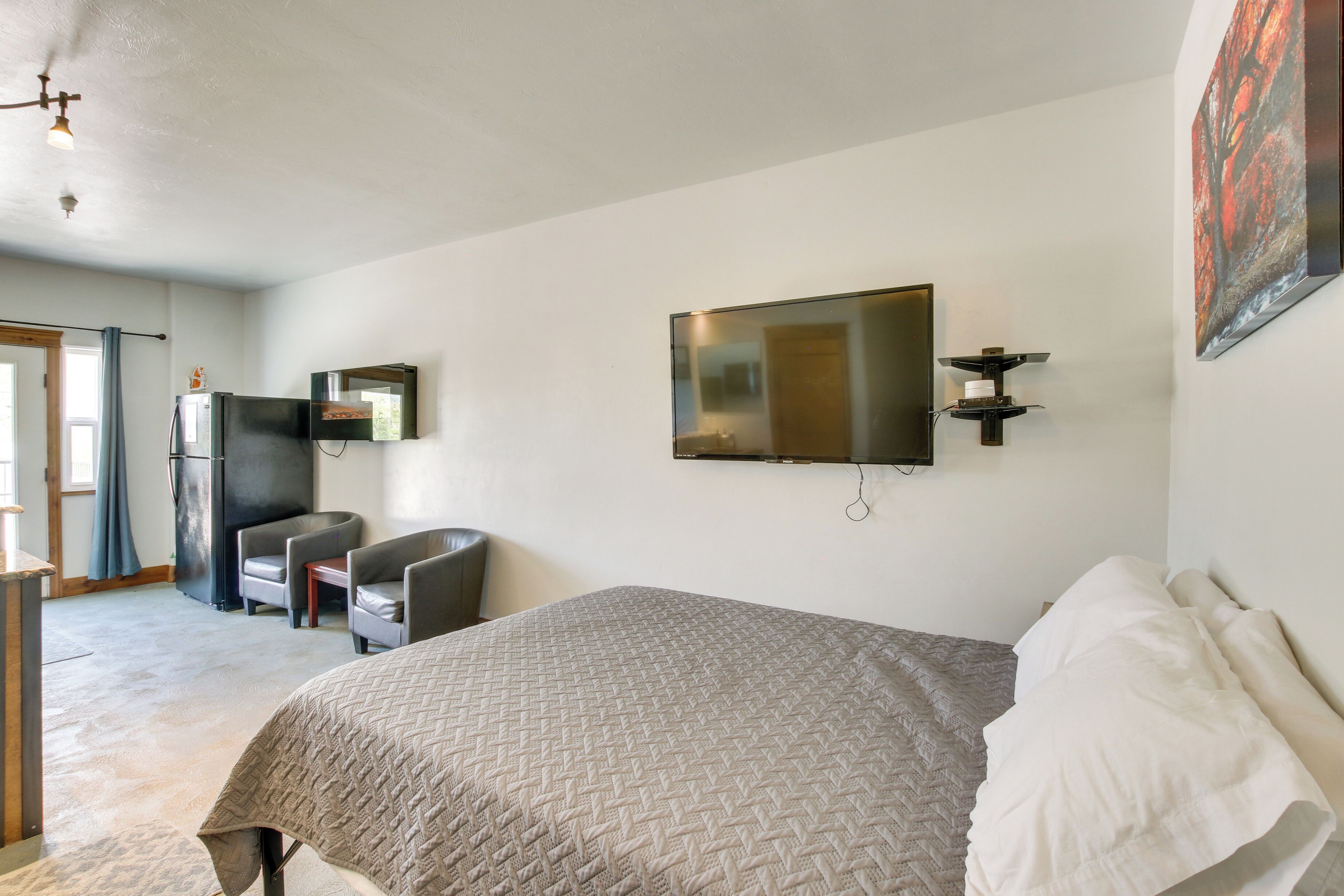Une chambre avec un lit, un téléviseur fixé au mur, une chaise et une petite table.