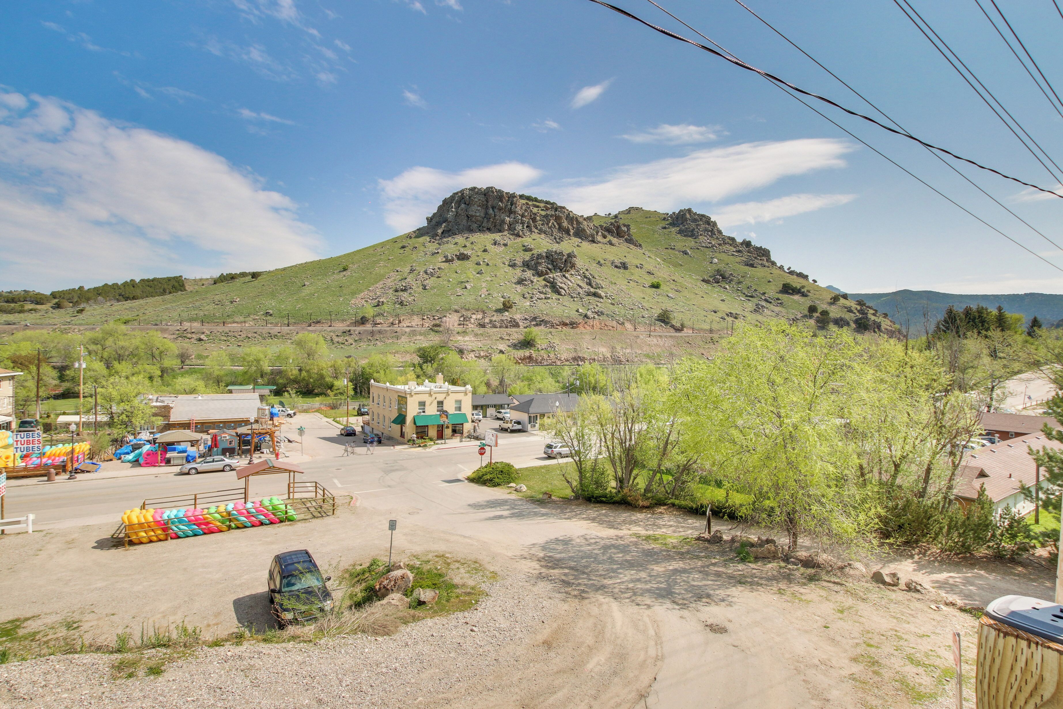 A small town with a prominent hill in the background, a parking lot with colorful inflatable tubes, and a few buildings with green awnings.