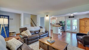 A spacious living room with a leather sofa, a wooden coffee table, and a view into the kitchen area. - Lakefront Vacation Rental w/ Views & Hot Tub! (Bracey)