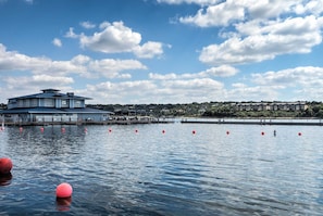 A waterfront hotel with a large building, dock, and red buoys.