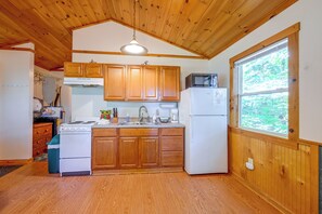 A kitchen with wooden cabinets, a stove, a refrigerator, and a window. - Cabin w/ Hot Tub - Near Nantahala Outdoor Center! (Bryson City)