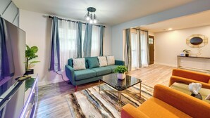 Un salon moderne avec un canapé vert, une table basse en verre et des fauteuils orange.