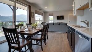 Une cuisine moderne avec un coin repas, de grandes fenêtres et une vue sur les montagnes.