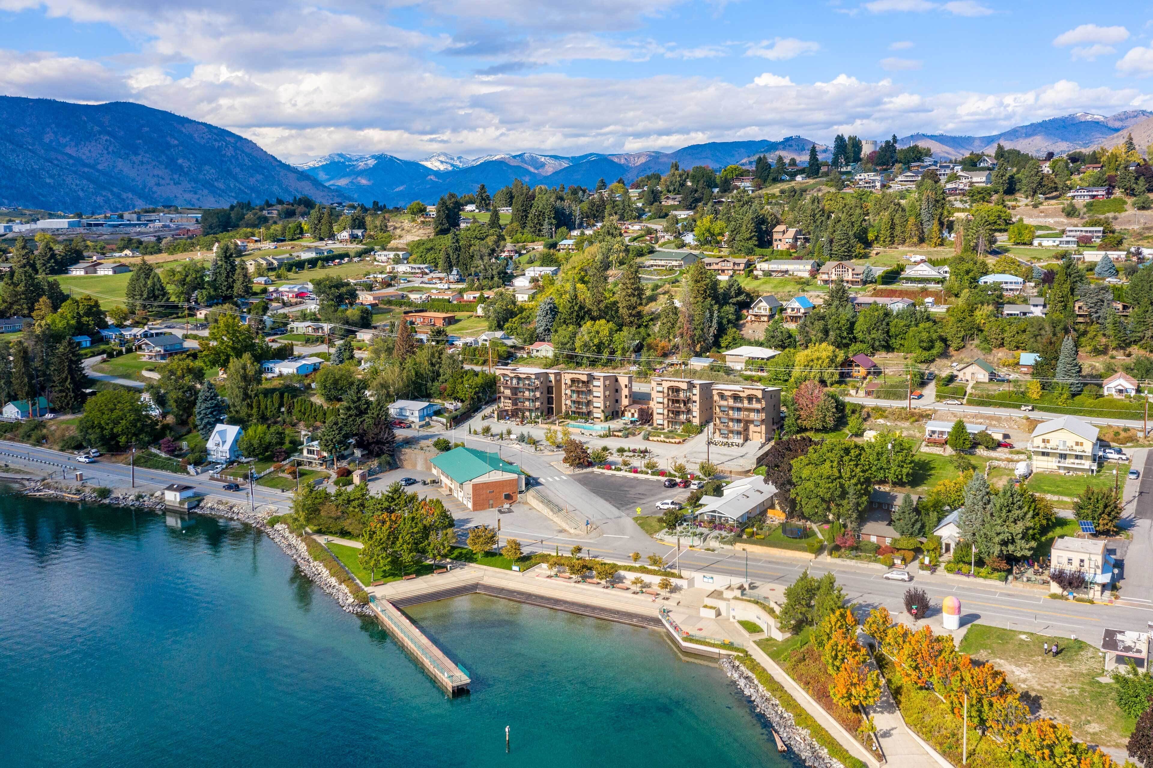 A coastal town with residential buildings, a marina, and mountains in the background.