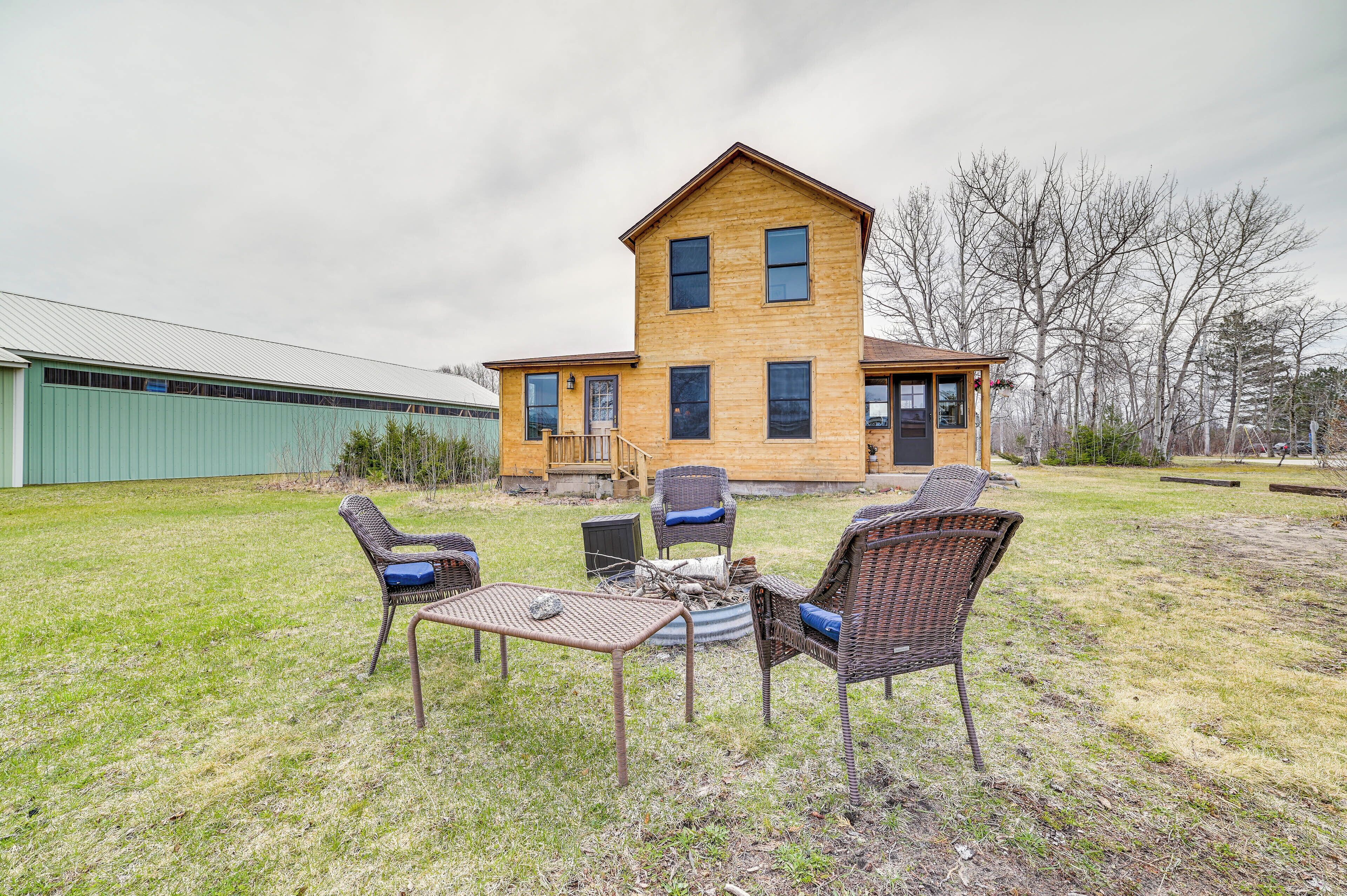 A two-story wooden house with a porch, a small deck, and a fire pit in the yard.