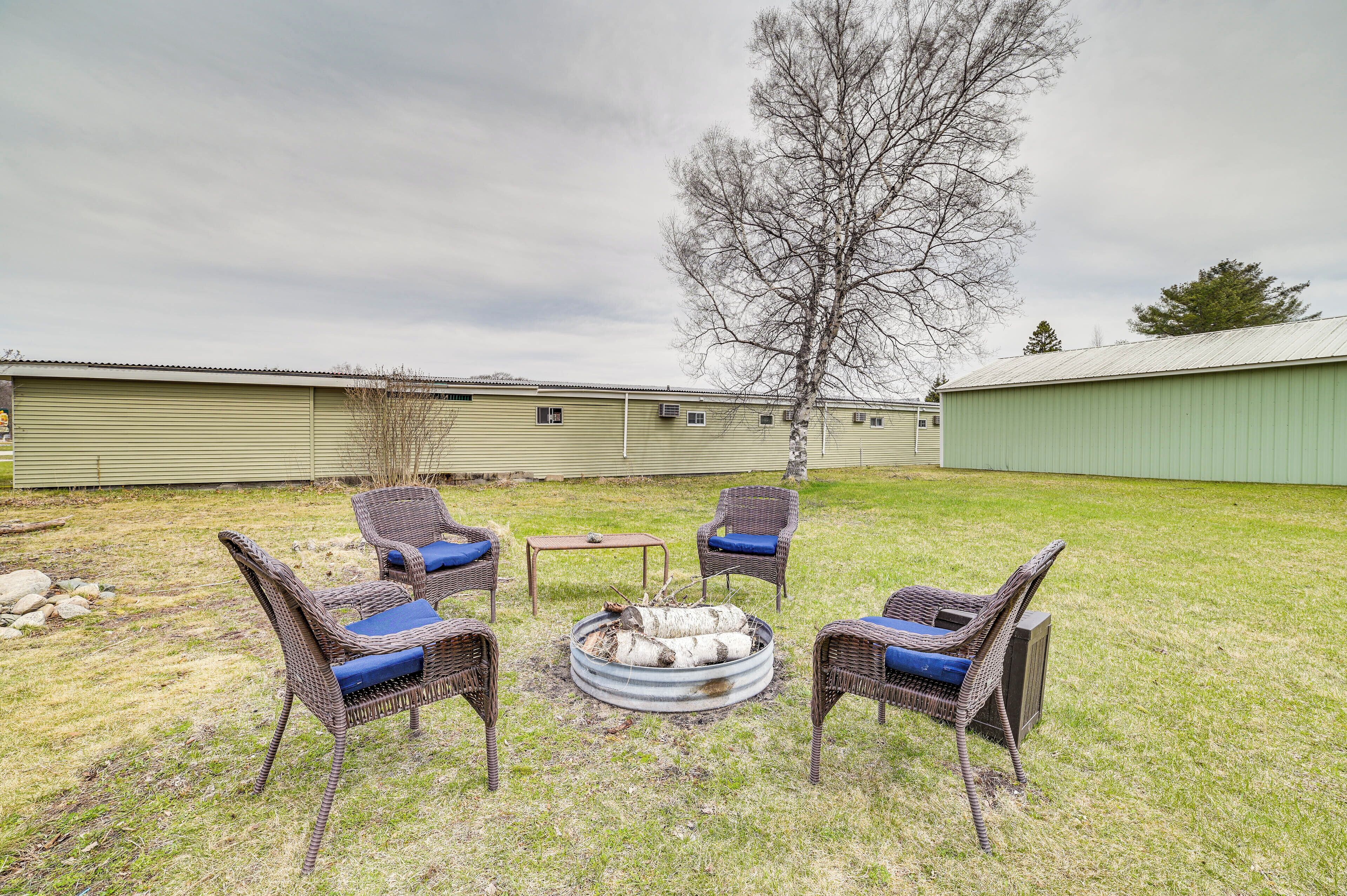 A backyard with wicker chairs, a small table, and a fire pit.