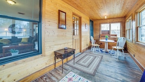 A wooden interior with a large window, a small table with a bowl, a white chair, and a rug on the floor. - Snowmobiling Hub! Mackinaw City Home 3 Mi to Beach (Mackinaw City)