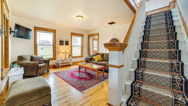 A spacious living room with a wooden staircase and a red rug. - Snowmobiling Hub! Mackinaw City Home 3 Mi to Beach (Mackinaw City)