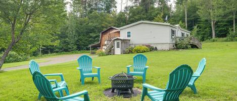 A house with a deck, surrounded by a grassy yard and trees.