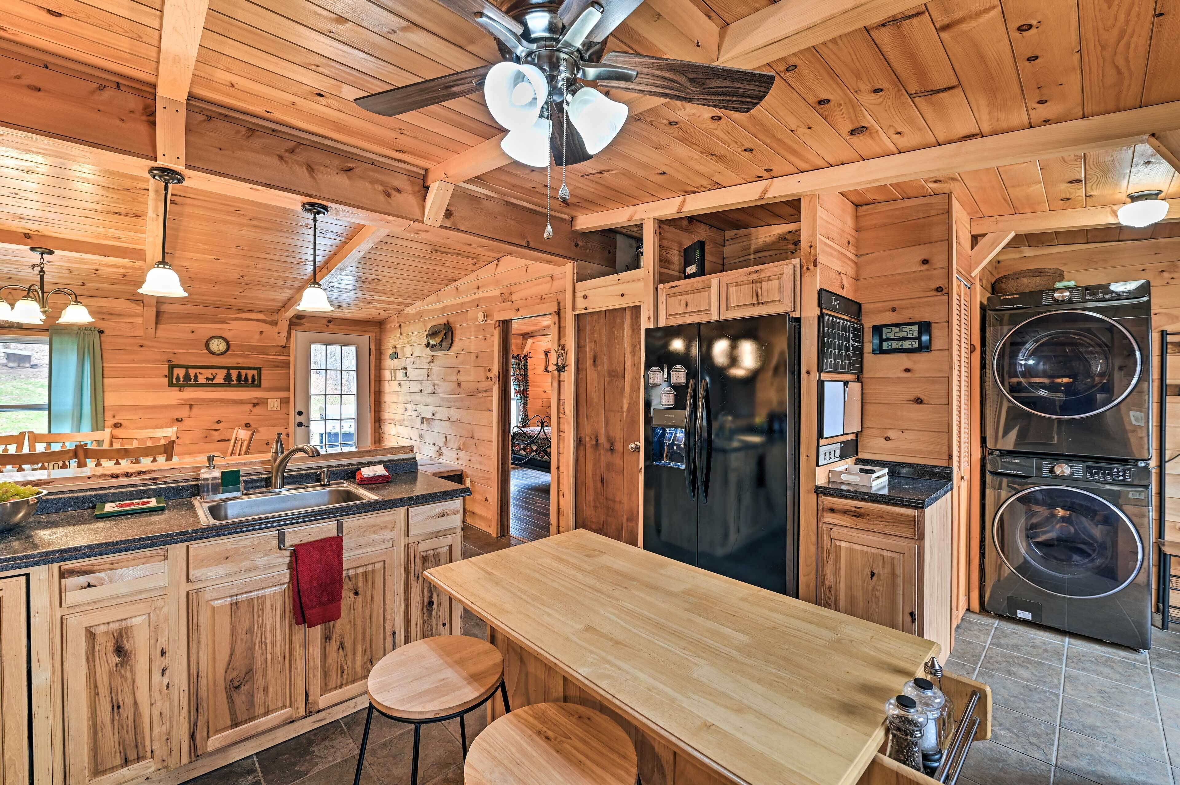 A wooden cabin interior with a kitchen, dining area, and a ceiling fan.