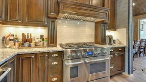 A kitchen with dark wood cabinets, a stainless steel range, and a tiled backsplash. - Luxurious Waterfront Retreat w/ Private Pond! (Ridgefield)