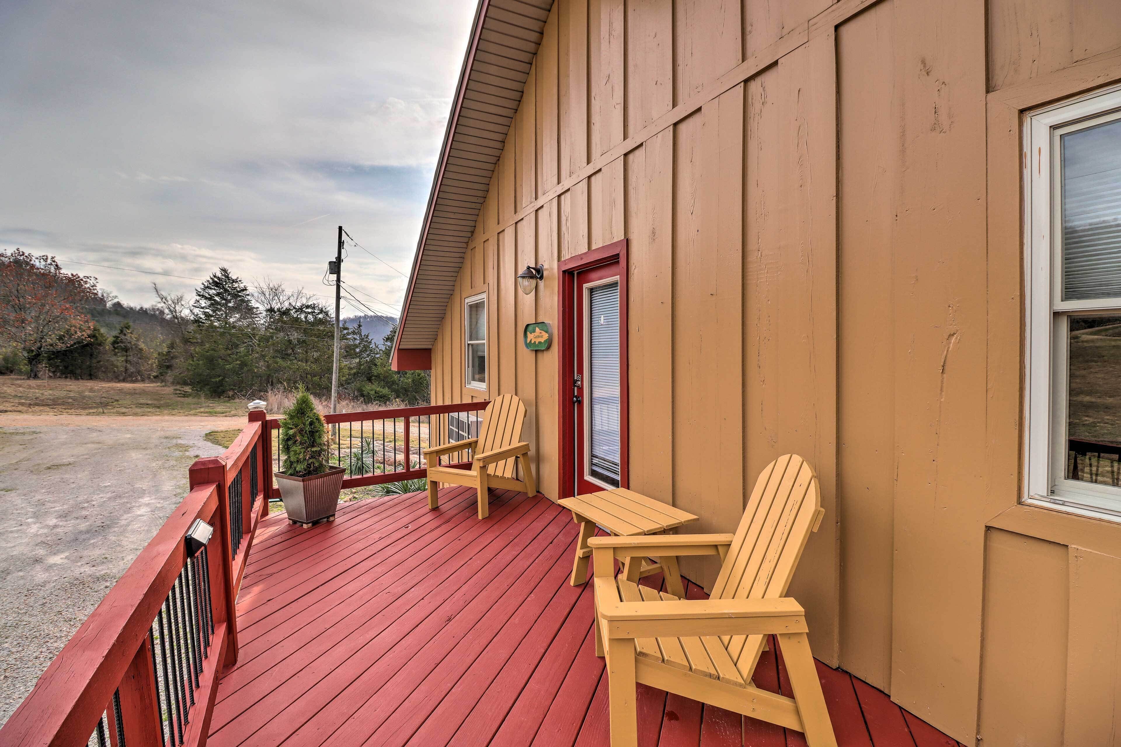 A wooden building with a red deck, two wooden chairs, and a small potted plant.