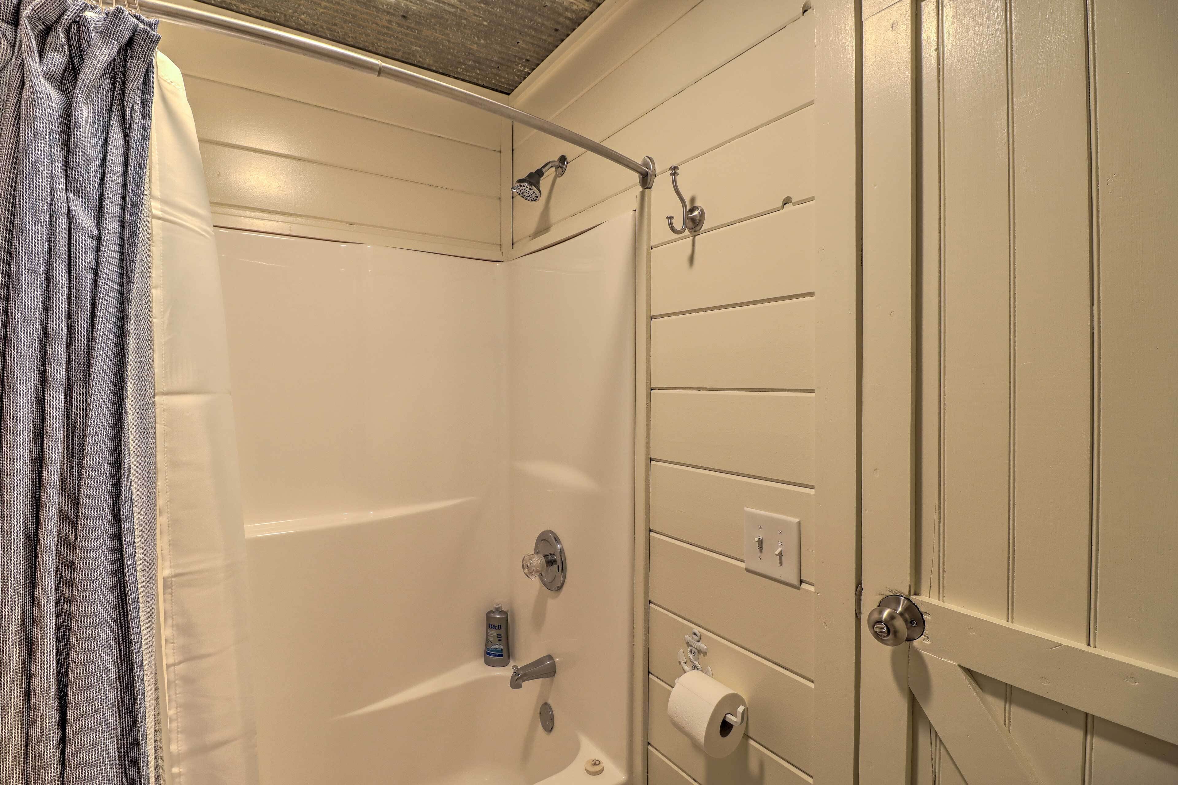A bathroom with a shower, toilet, and towel rack.