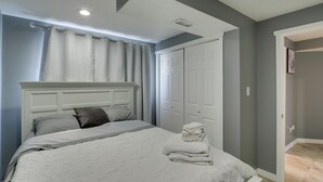 Une chambre à coucher comprenant un lit, une tête de lit, une armoire et une porte donnant sur une autre pièce.