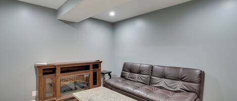 A living room with a brown leather sofa, a wooden entertainment center, and a granite coffee table.