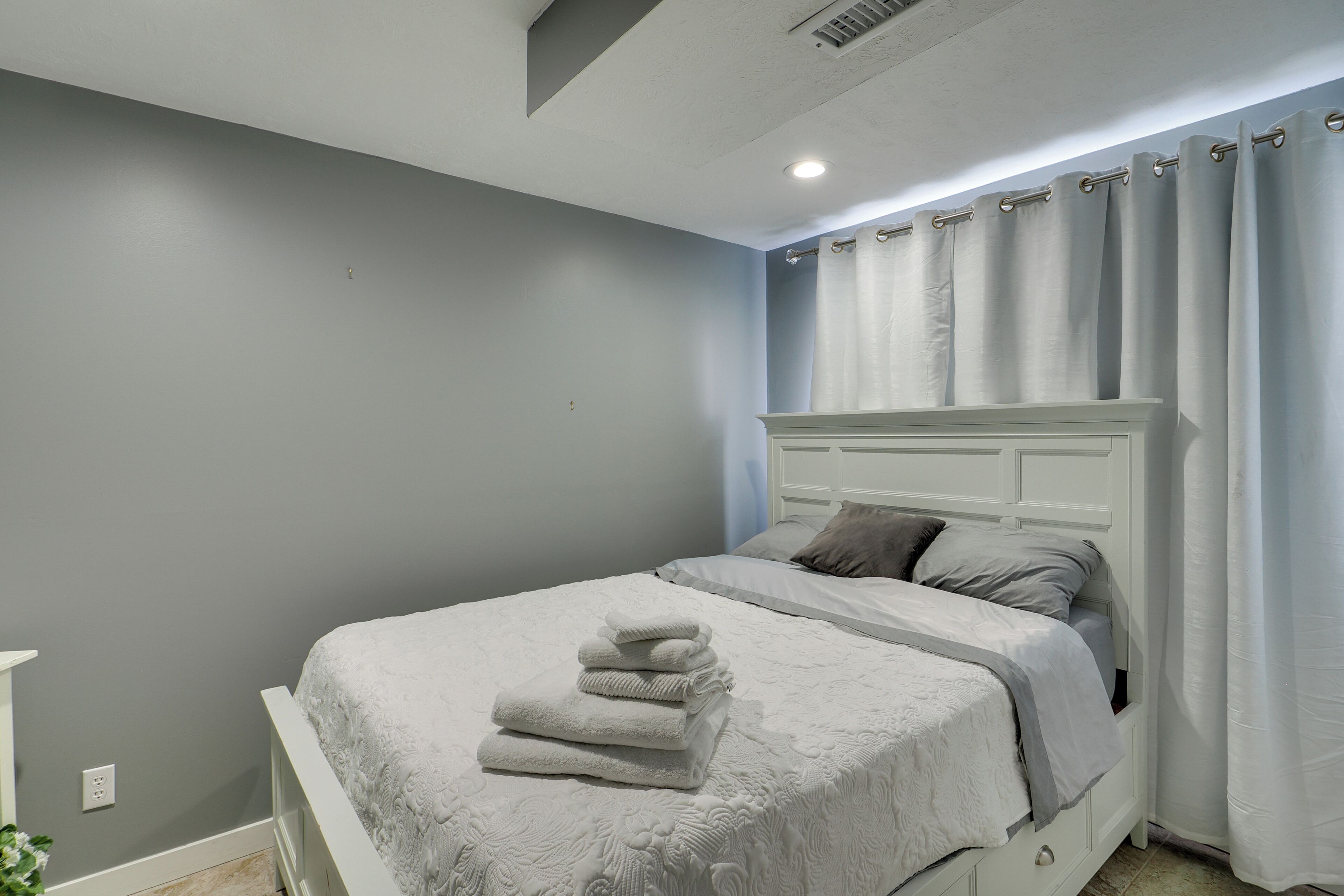 A bedroom with a bed, a bedside table, and a window with curtains.