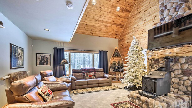 A cozy living room with a stone fireplace, leather sofas, and a Christmas tree. - Phelps Cabin on 26 Acres w/ Fire Pit! (Phelps)