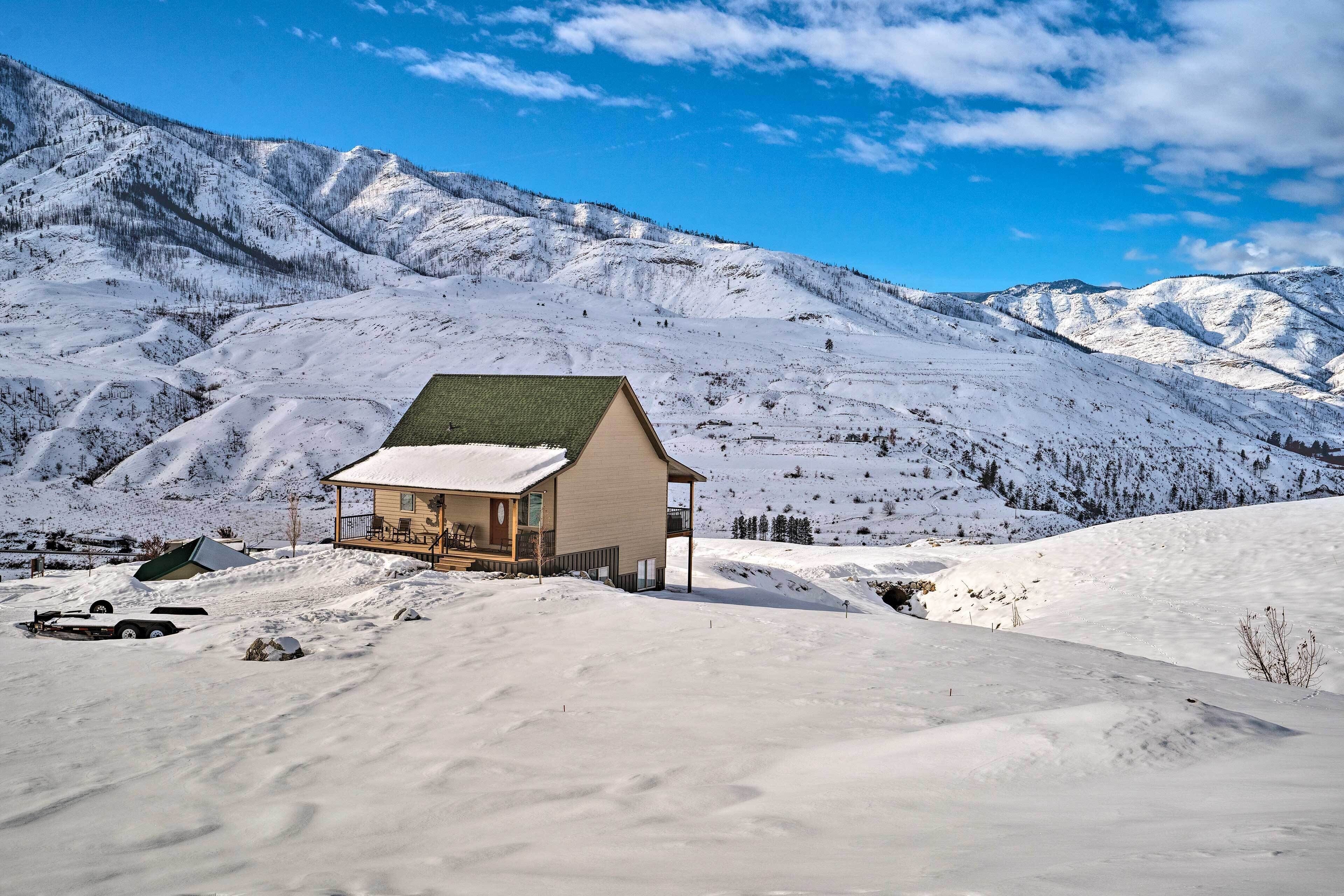 A snow-covered mountain landscape with a single building featuring a balcony and a green roof.