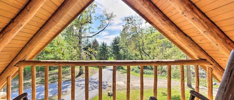 Une pièce aménagée sous les combles, avec un plafond en bois et une vue sur une zone boisée.
