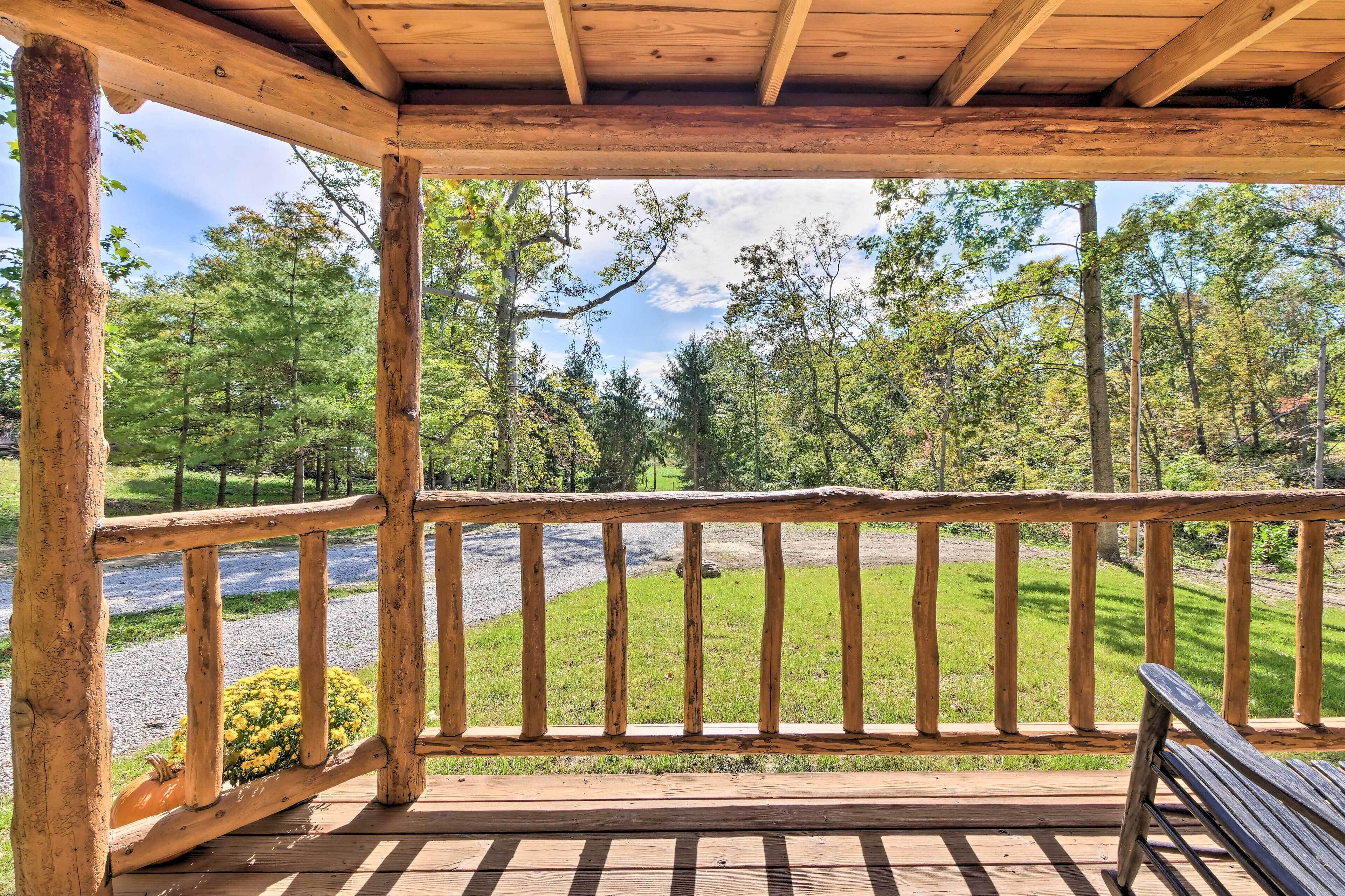 A wooden deck with a bench, overlooking a grassy area with trees and a gravel path.