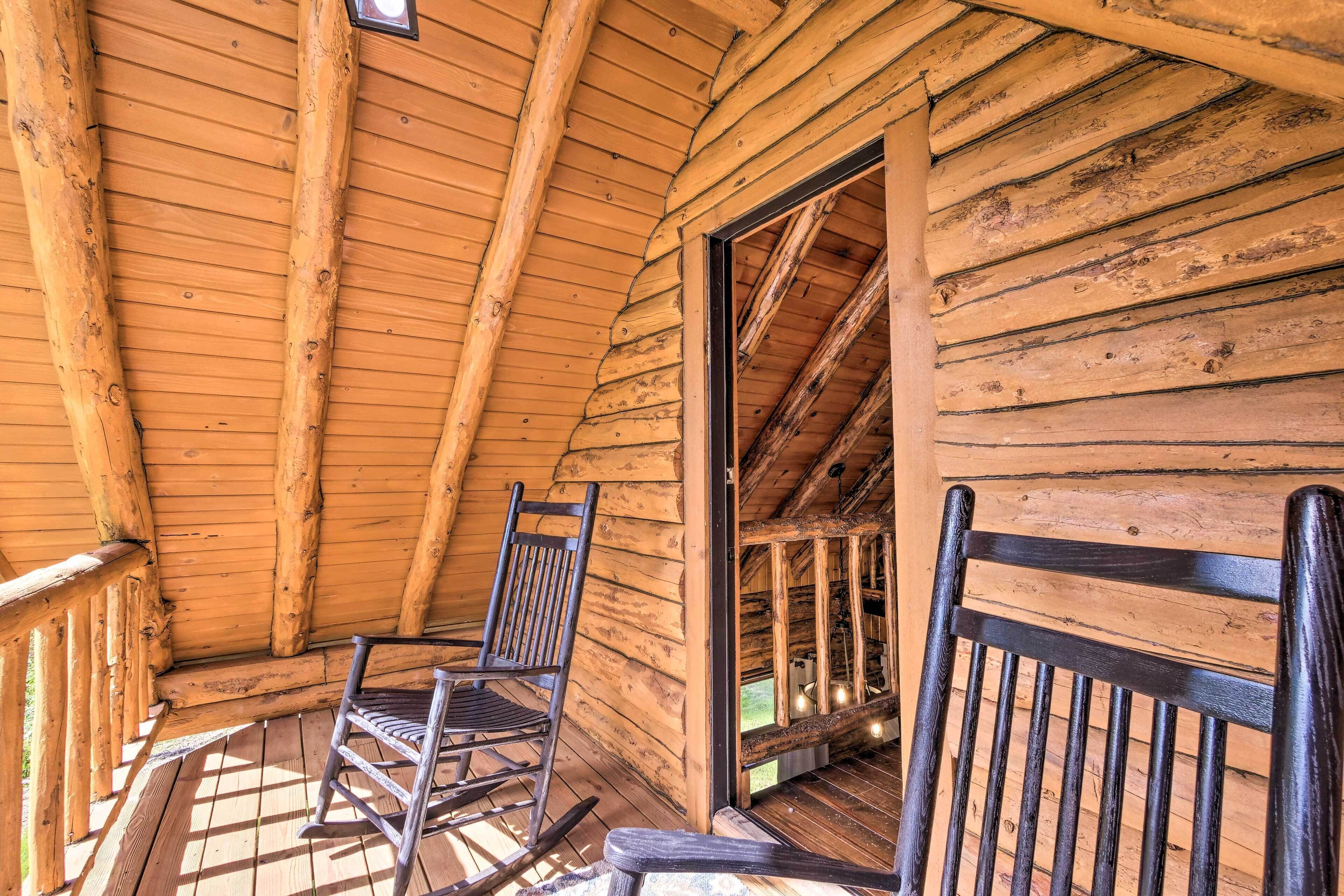 A wooden cabin with a porch, two rocking chairs, and a visible door leading to another room.