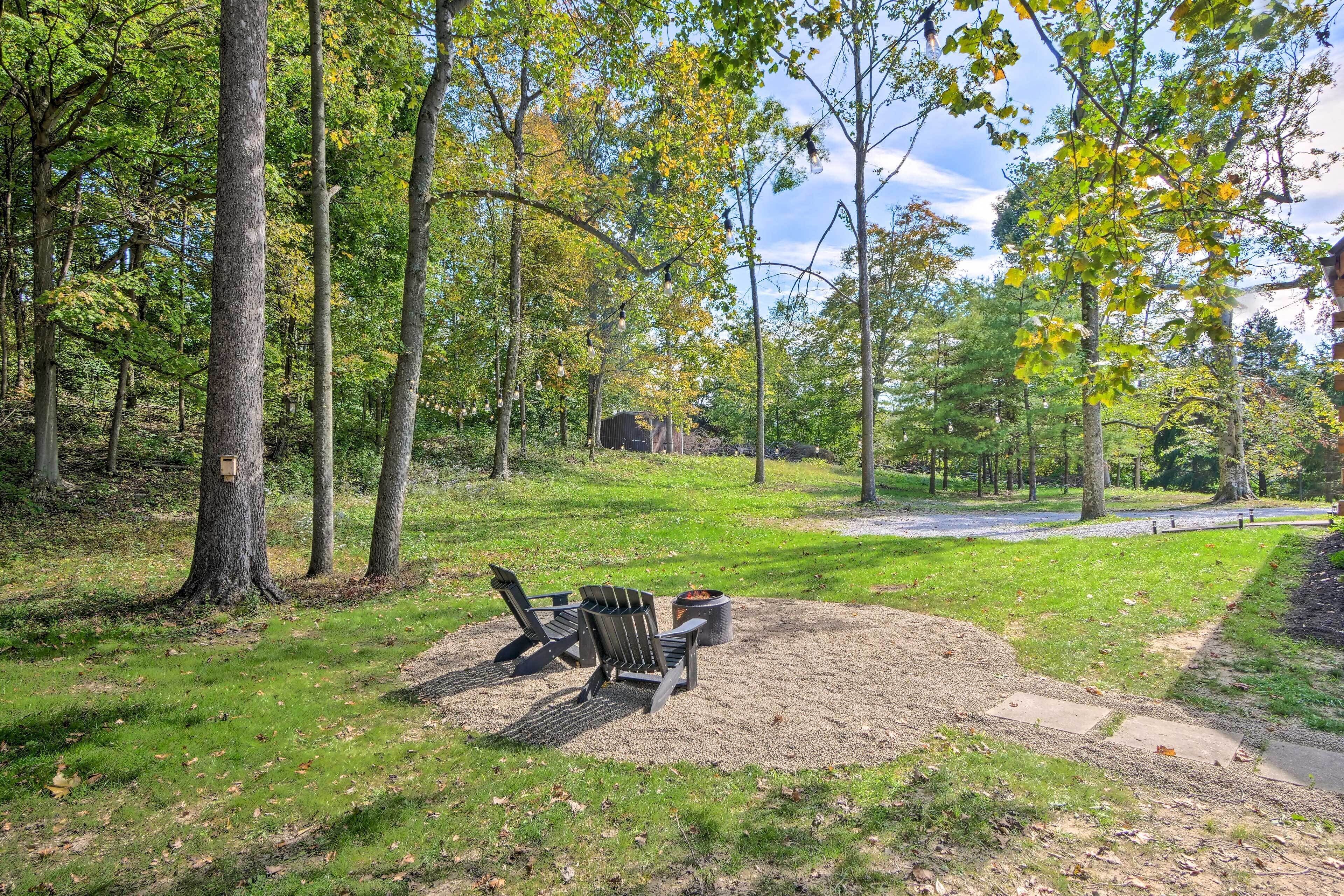 Un parque con dos sillas Adirondack, un hogar para fuego y una zona de grava.