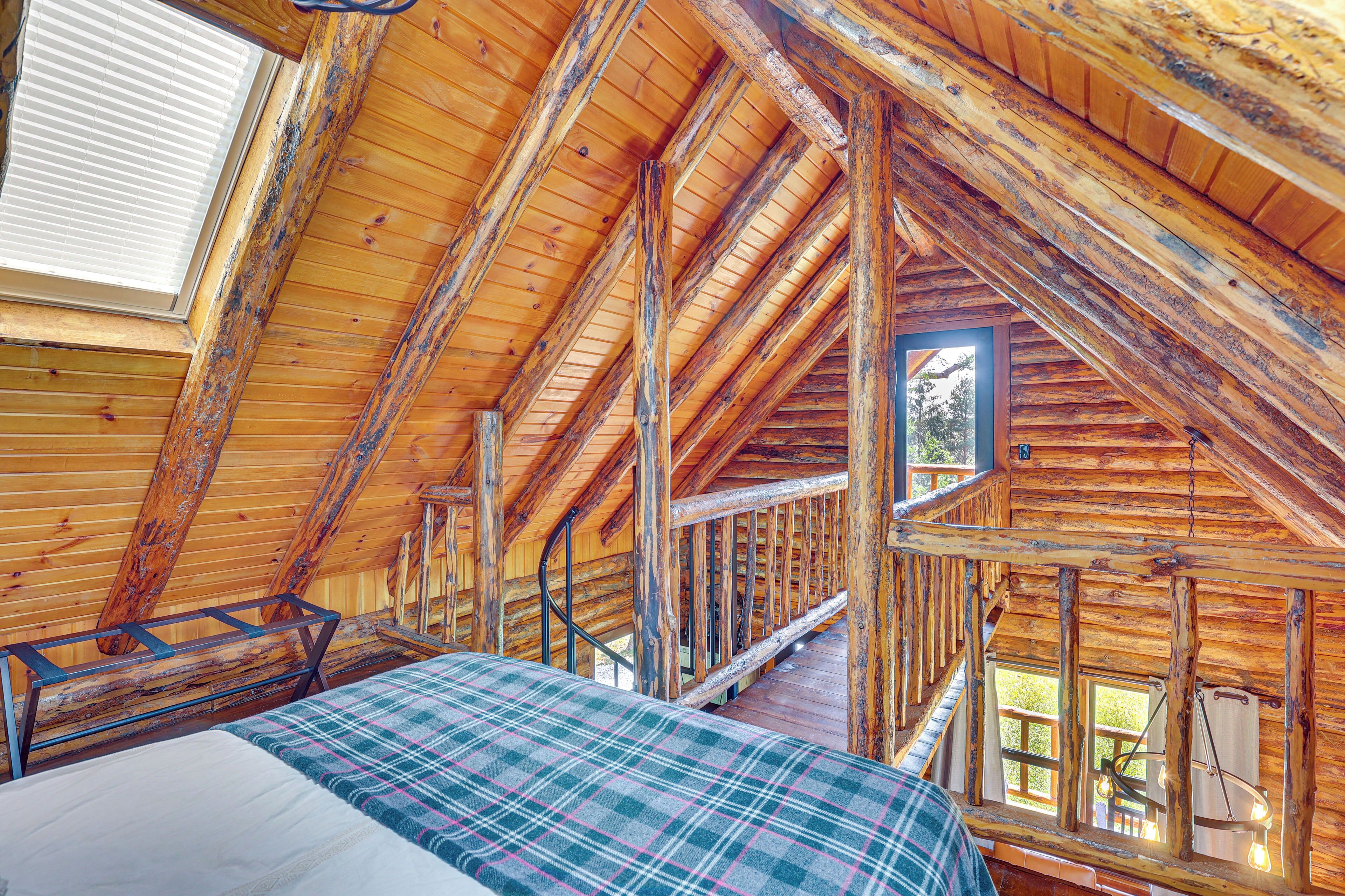 Una cabaña de madera con habitación en el altillo, una escalera y un ventanal con vistas.