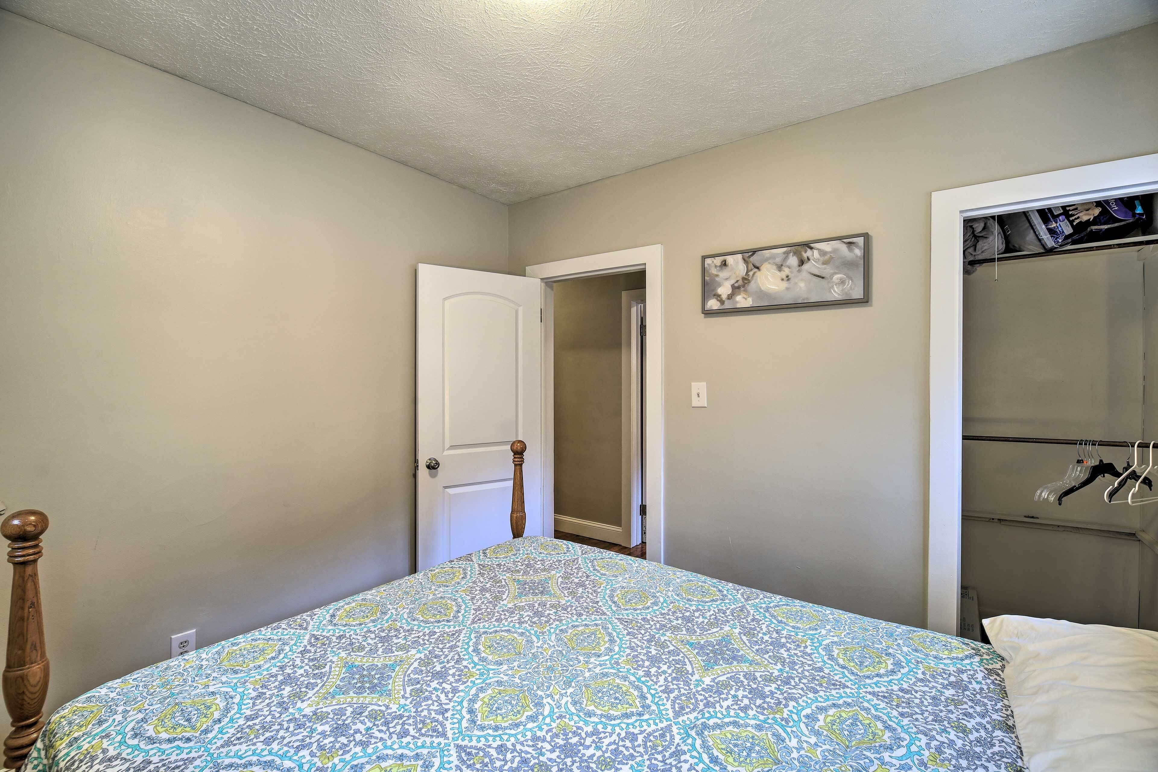 A bedroom with a bed, a closet, and a door leading to another room.