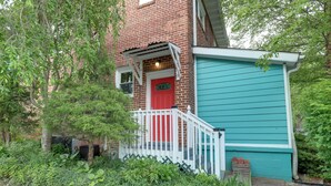 A red brick house with a white porch and a blue shed.