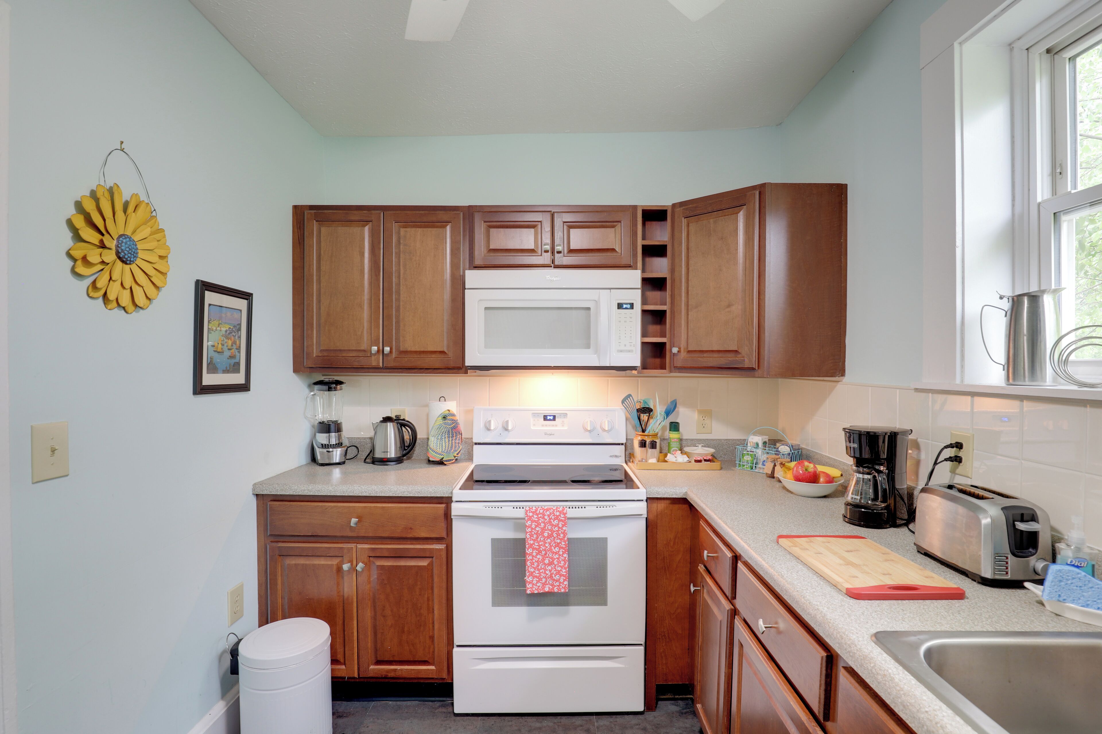 A kitchen with wooden cabinets, a white stove, and a sink.