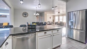 Una cocina moderna con un refrigerador de acero inoxidable, una isla grande con cubierta negra e iluminación colgante.