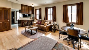 A spacious living room with a sofa, coffee table, and dining area. A kitchen is visible in the background. - Pet-friendly Blue Mounds Vacation Rental w/ Yard! (Blue Mounds)