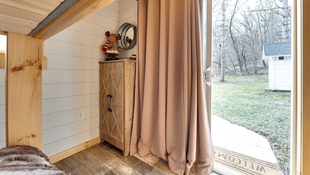 A room with a wooden ceiling, a wooden cabinet with drawers, a mirror, and a beige curtain. - Pet-friendly Blue Mounds Vacation Rental w/ Yard! (Blue Mounds)