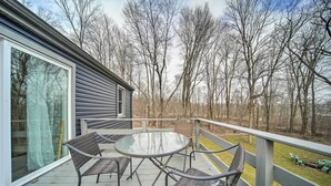 A deck with a glass table and chairs, overlooking a wooded area. - Meadville Home: Private Yard & Fishing Nearby (Meadville)