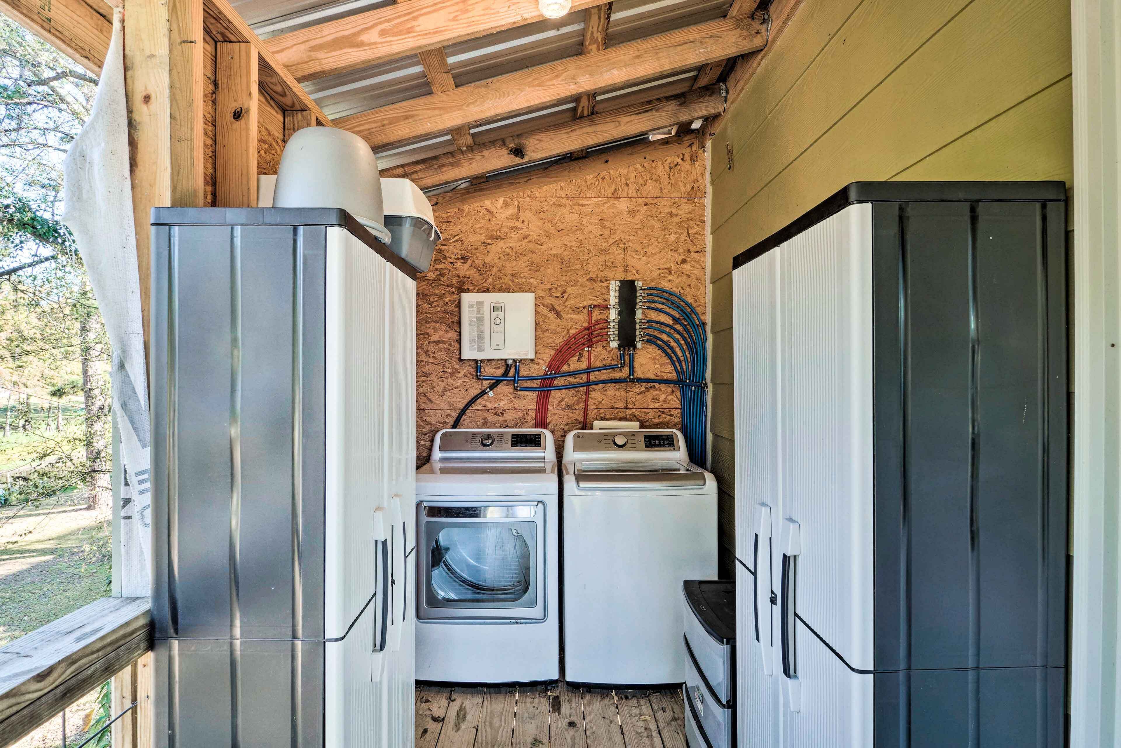 Une petite buanderie équipée de deux machines à laver et d’un sèche-linge, avec des poutres en bois au plafond et des câbles électriques apparents.