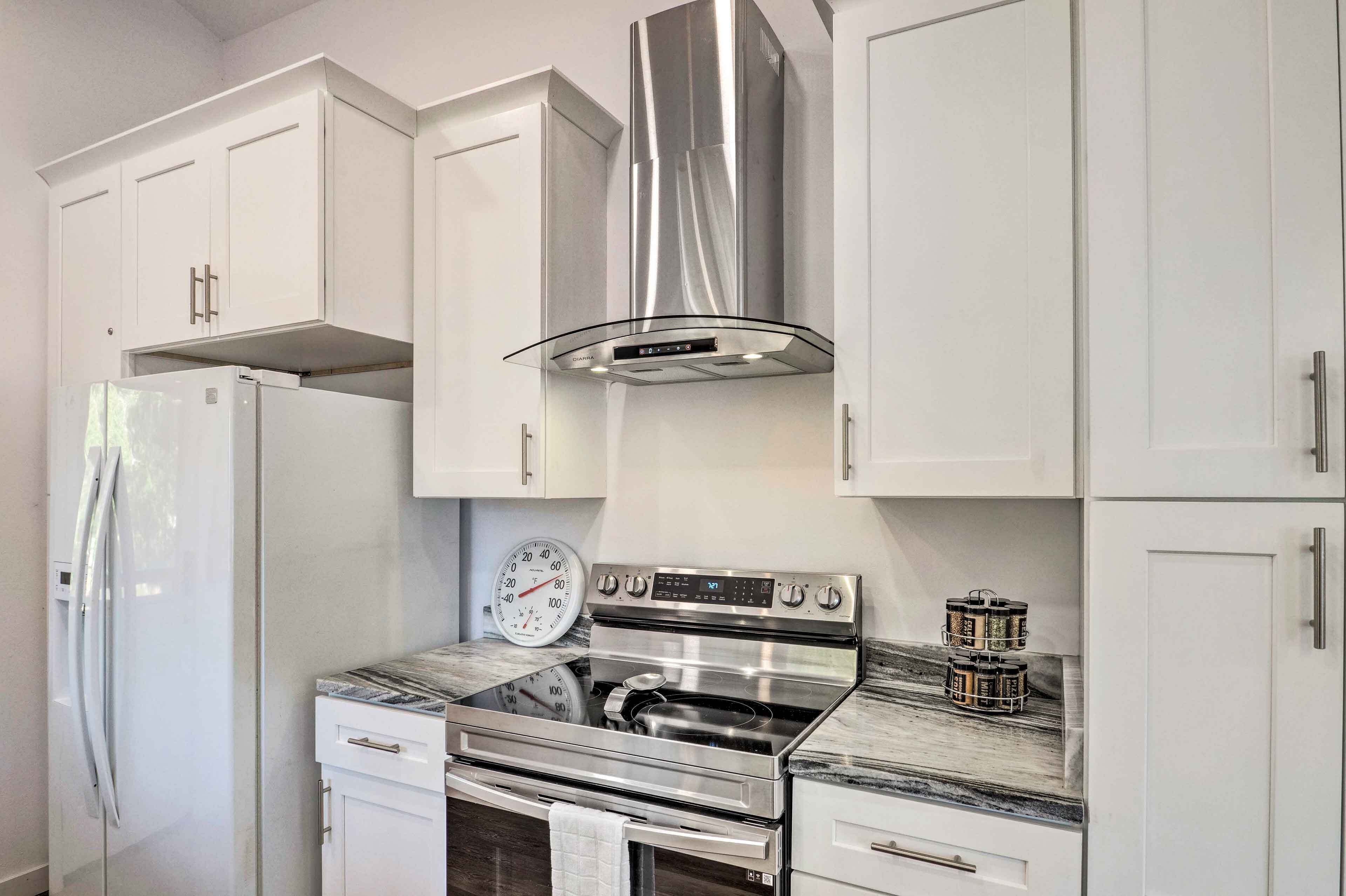 A modern kitchen with stainless steel appliances, white cabinetry, and a built-in oven.