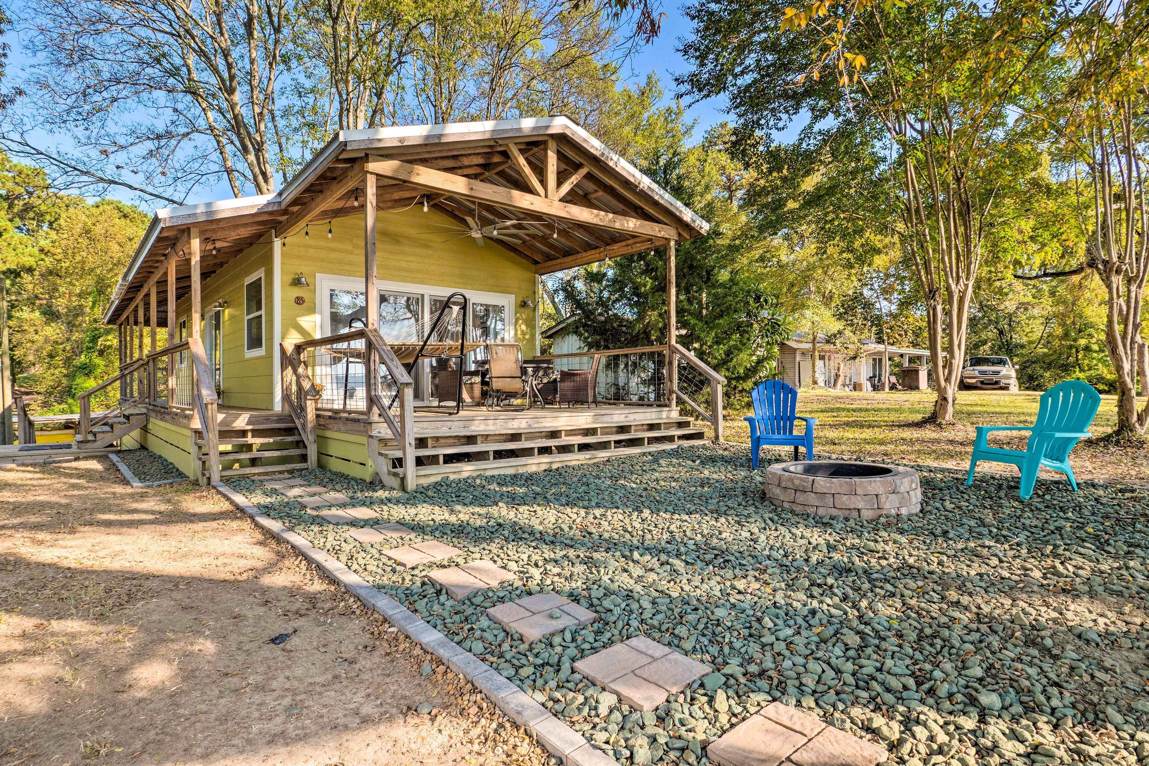 A rustic cabin with a wooden deck, outdoor seating, and a fire pit.