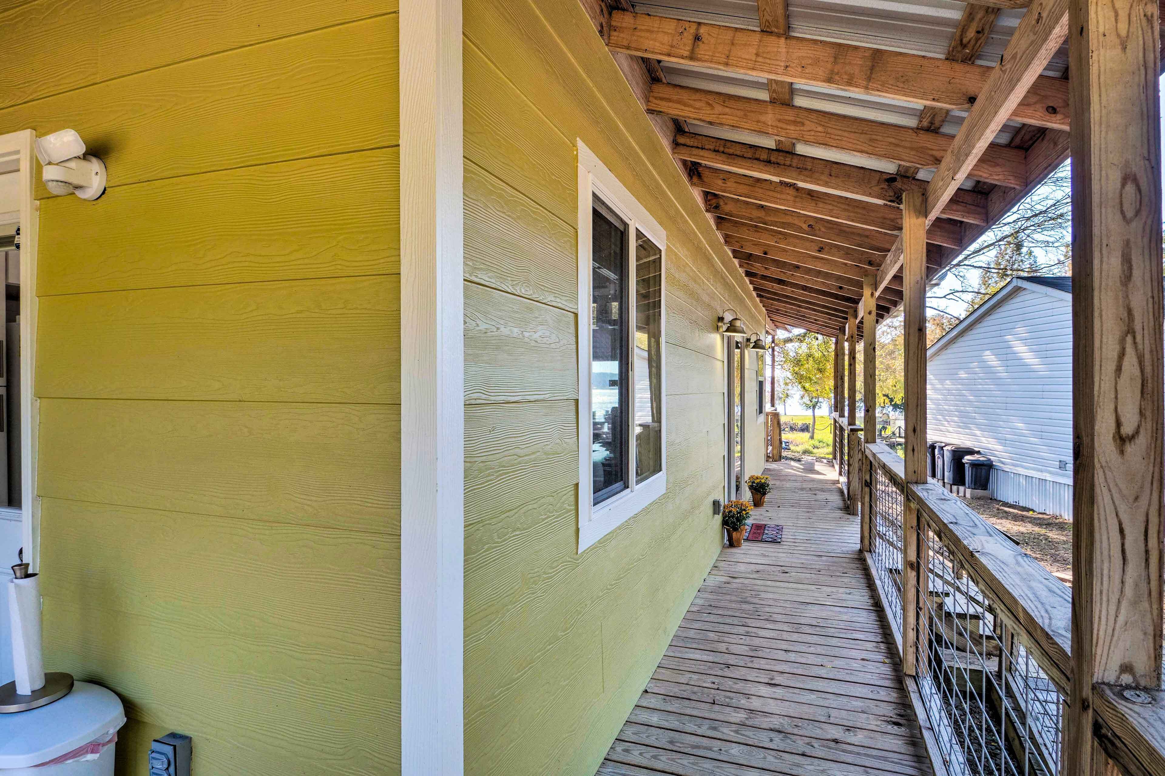 A covered porch with a wooden railing, a wooden floor, and a window.