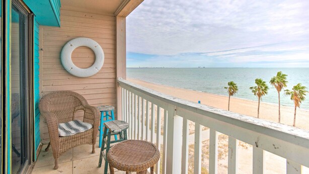 A balcony with wicker furniture, a lifebuoy, and a view of the beach. - Oceanfront Corpus Christi Condo w/ Pool! (Corpus Christi)