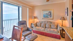 A living room with a sofa, a chair, a table, and a ceiling fan. - Oceanfront Corpus Christi Condo w/ Pool! (Corpus Christi)