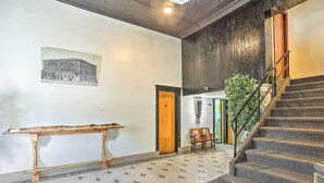 A hallway with a patterned floor, a wooden bench, a staircase, and a door leading to another room.
